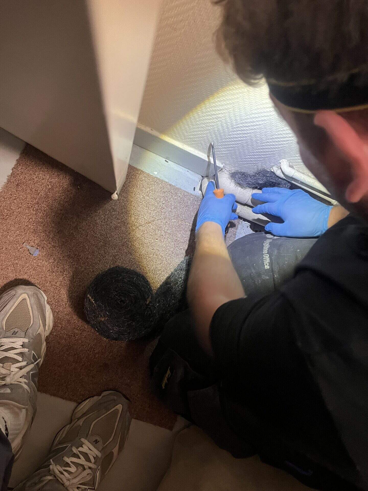 Technicien anti-nuisibles en train de boucher un passage de rats avec du matériel de dératisation